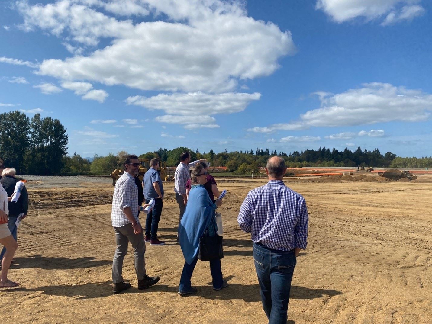 People walking in a dirt field construction site.