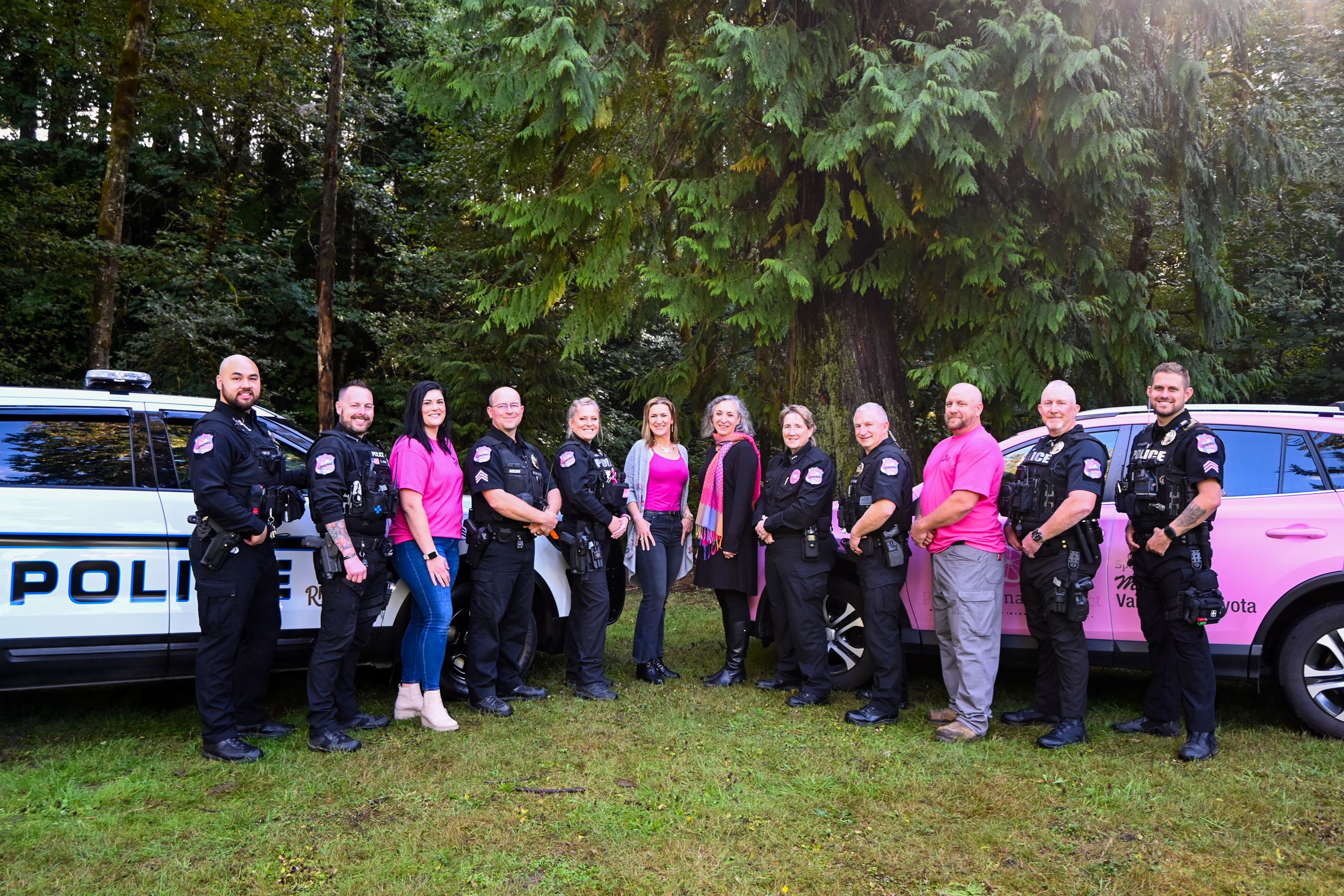 Police officers with bright pink patches pose with the mayor, Susan Stearns, and city staff.