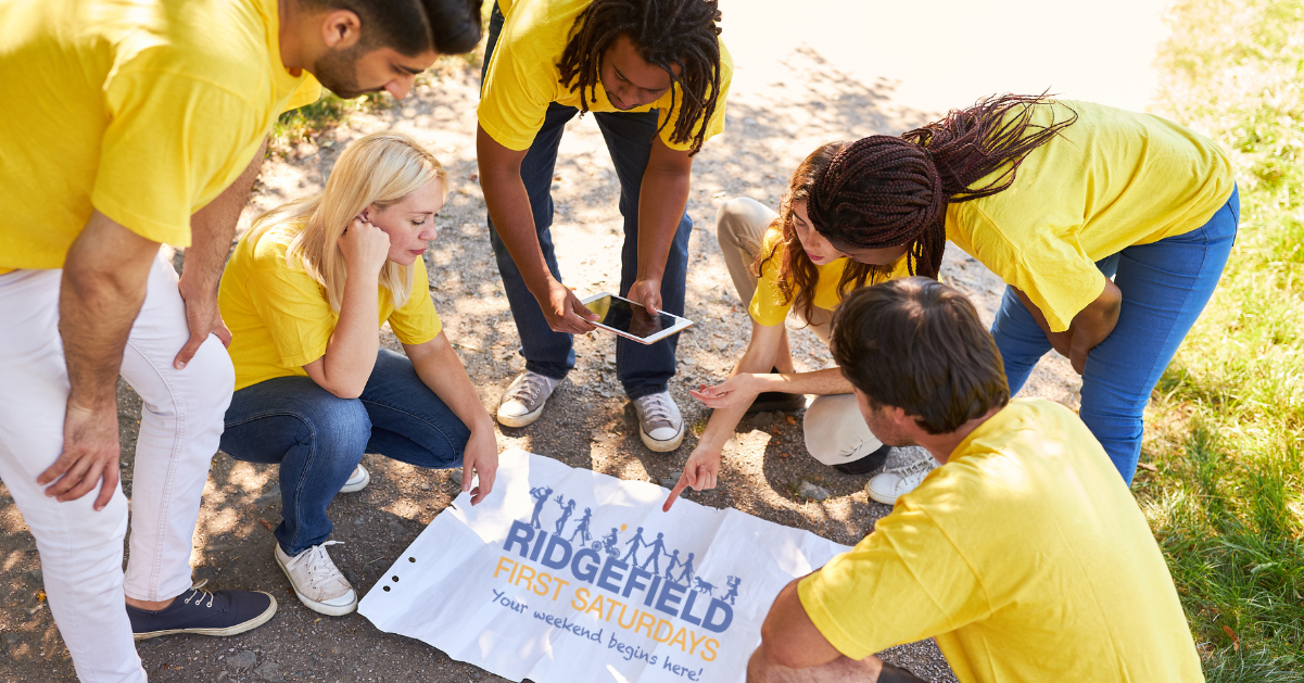 Group of people looking at large Ridgefield First Saturdays Logo