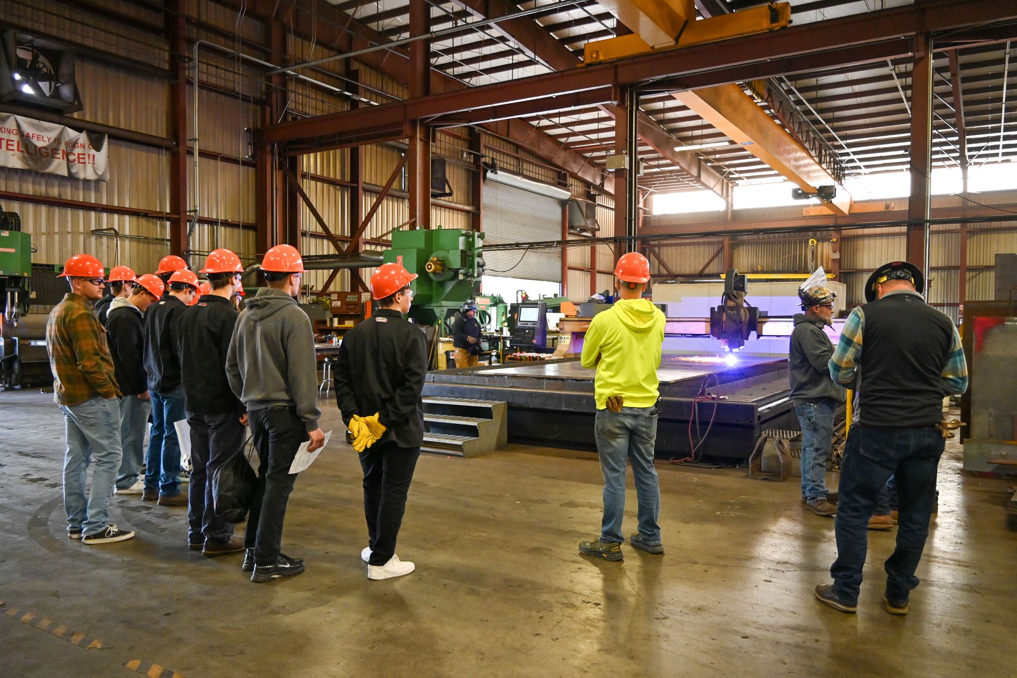 Students watch as shapes are cut on the plasma table.